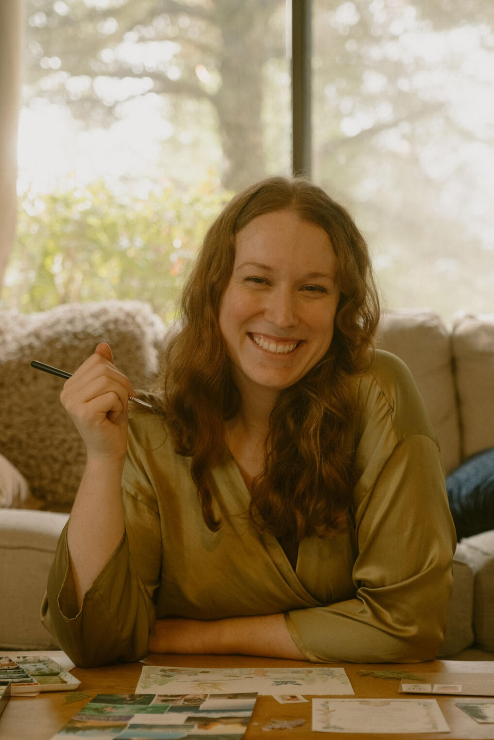 About Me Photo of Amy, watercolor artist behind Fablefern Studio, sitting and painting invitations.